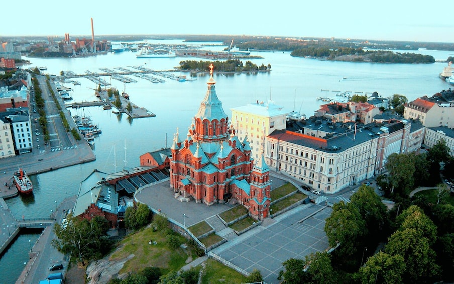 A large red church with a golden dome, surrounded by a cityscape with buildings and a river. 1