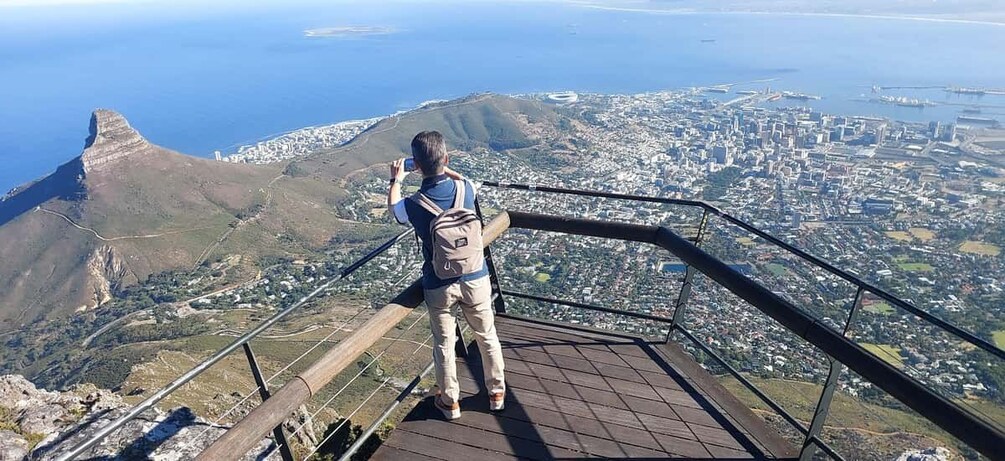 A person taking a photo of a coastal city from a high vantage point. 3