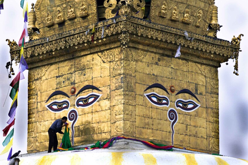 A temple with intricate carvings and a person painting a face on the wall. 5