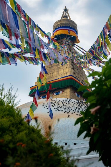 A large stupa with colorful prayer flags and a painted face. 1