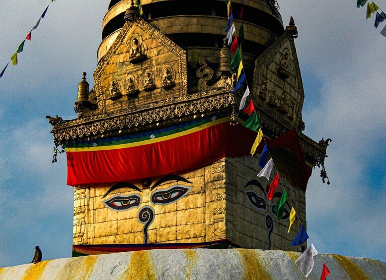 A golden stupa with a face, adorned with flags and intricate carvings. 3