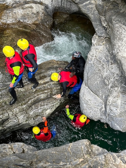 Un grupo de personas con cascos y chalecos salvavidas cerca de un cuerpo de agua rocoso. 1