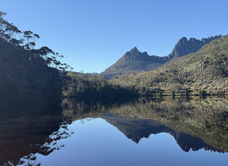 A calm lake reflecting the surrounding mountains and dense forest. 4