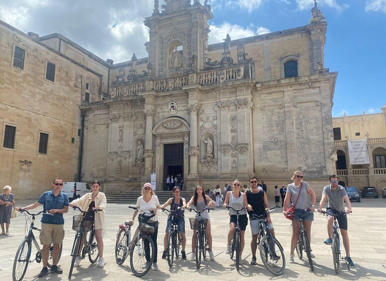 A group of people on bicycles in front of a historic building with ornate architecture. 3