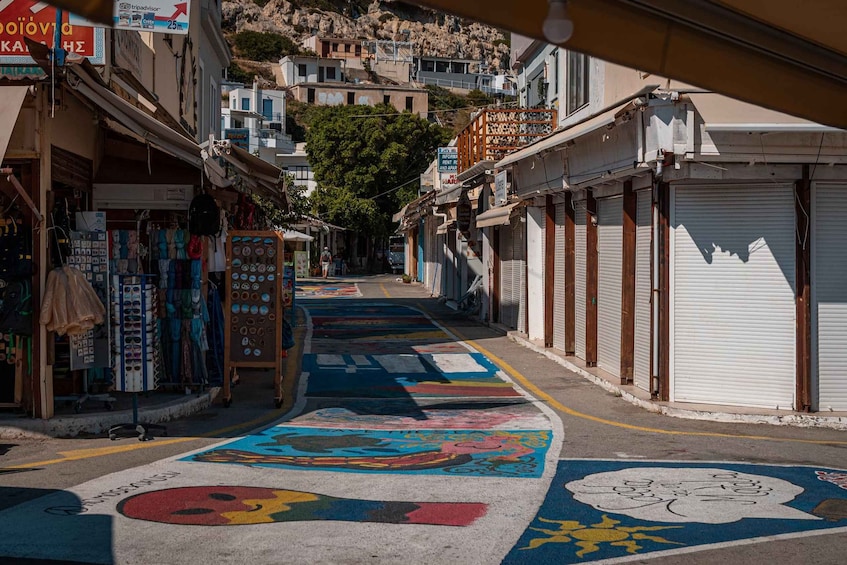 A narrow street with colorful pavement designs, closed shops, and buildings on a hillside. 5