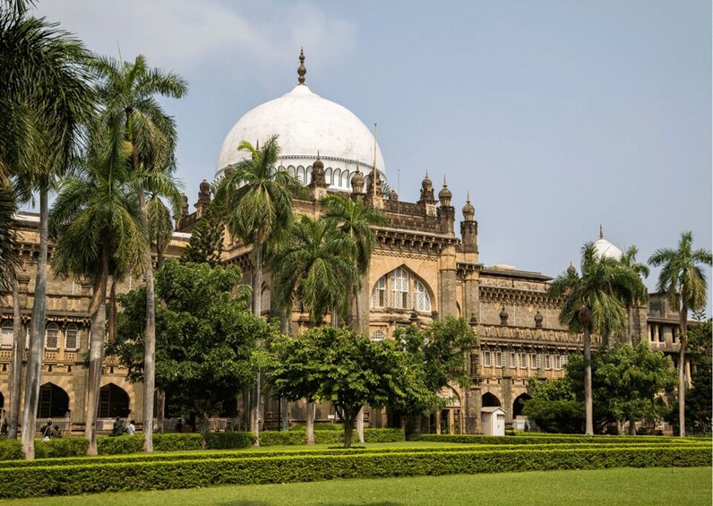 A large historic building with a prominent dome, surrounded by palm trees and manicured gardens. 4