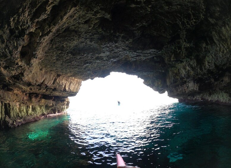 A person swimming in a cave with a large opening to the sea. 2