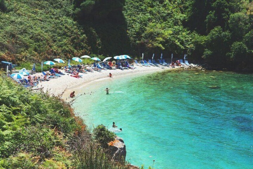 A beach with clear turquoise water, surrounded by lush greenery. 5