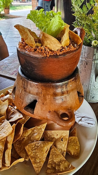 Un pot en terre cuite rempli de croustilles, avec une verdure à feuilles sur le dessus. 2