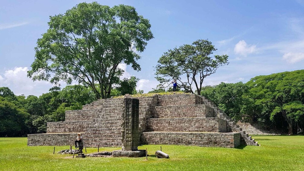 An ancient stone pyramid surrounded by lush greenery. 1