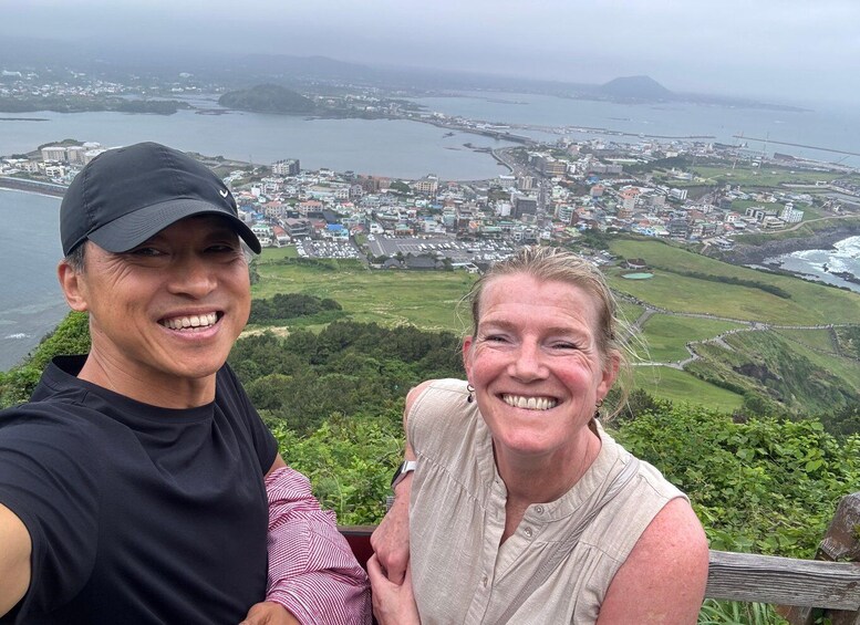 A couple taking a selfie with a coastal cityscape in the background. 1