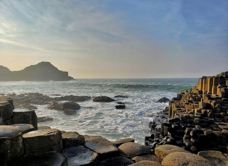 A rocky coastline with waves crashing against large boulders and a sea wall. 2
