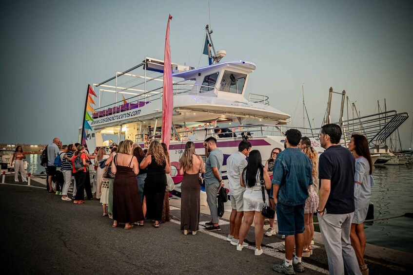A group of people standing by a boat at a marina. 5