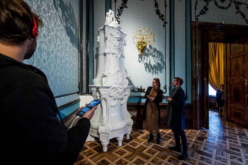 A grand room with ornate white furniture, a chandelier, and patterned wallpaper. 4