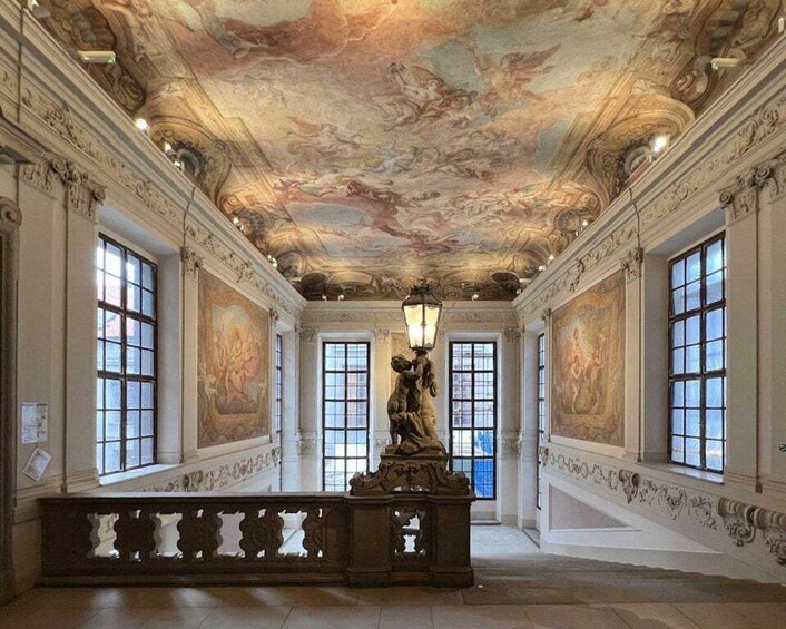 An ornate room with a high ceiling, large windows, and a statue. 3