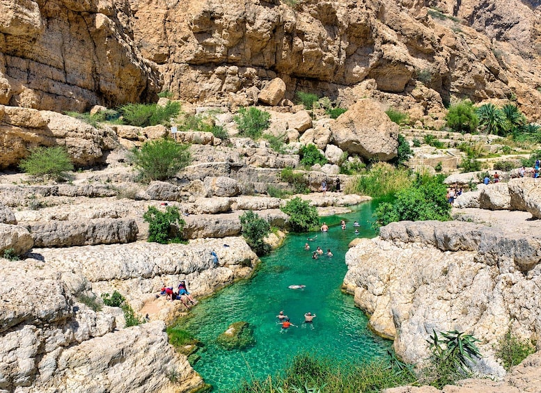 A rocky landscape with a clear water stream surrounded by large boulders and sparse vegetation. 1
