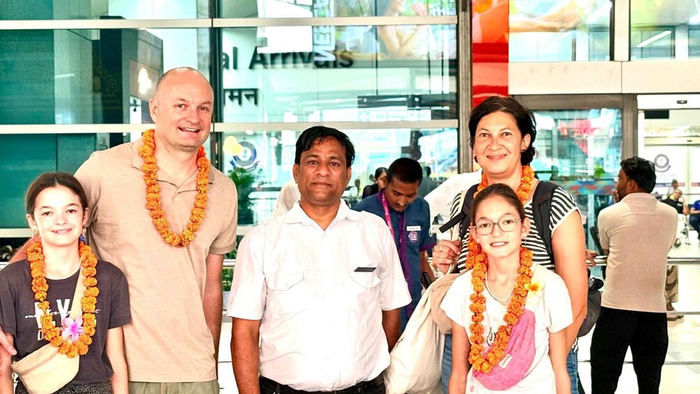 A group of people standing in front of a building with a sign that reads 'Arrivals'. 2