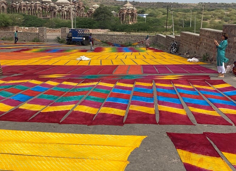 Un colorido tejido extendido en el suelo con gente caminando alrededor. 3