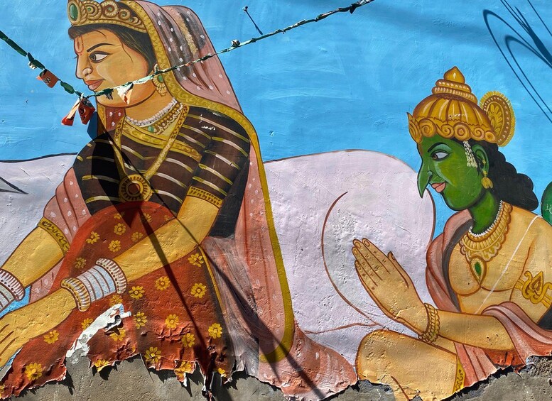 Un mural con dos figuras, una vestida con atuendo tradicional y la otra con un traje verde, y un cielo despejado al fondo. 2