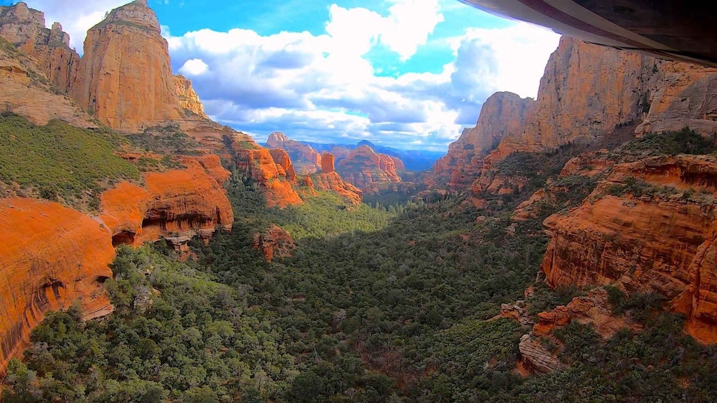 A canyon with red rock formations and a dense forest. 2