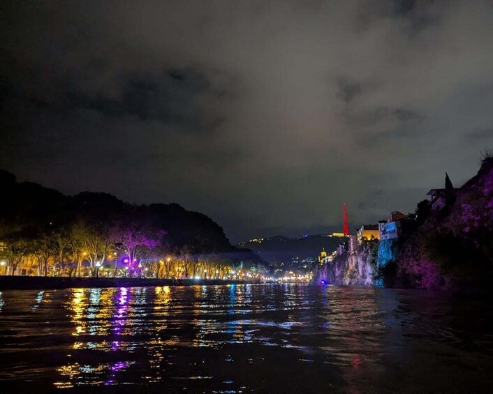 A river at night with illuminated buildings and trees reflecting on the water. 3