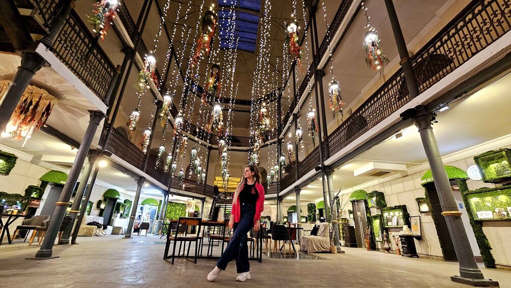 A spacious indoor area with high ceilings adorned with hanging lights and greenery. 5
