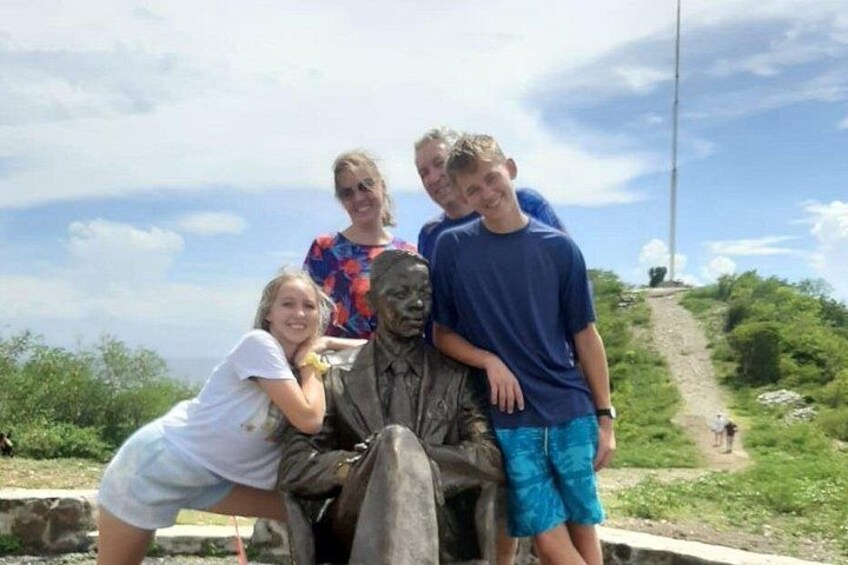 Un grupo de personas posando junto a una estatua en un entorno natural. 2