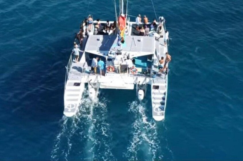 A white boat with multiple decks and passengers, sailing on a blue ocean. 3