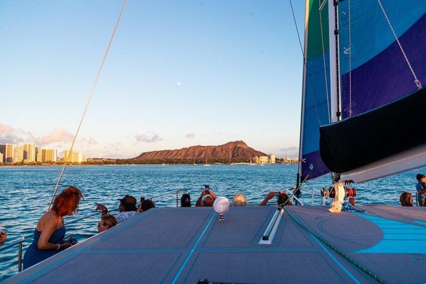 A sailboat with people on deck, water, and a distant mountain range. 3