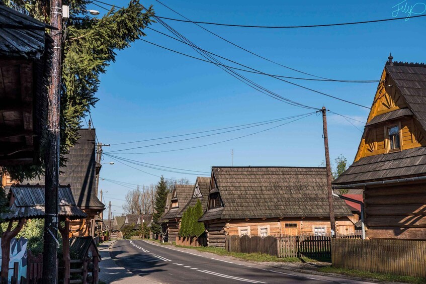 Une rue bordée de maisons traditionnelles en bois, un ciel d’un bleu éclatant et des lignes électriques qui la traversent. 3