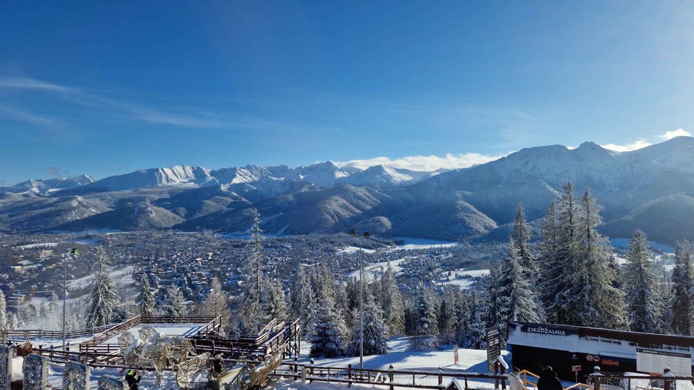 Un paysage montagneux enneigé, avec une station de ski au premier plan et une ville en contrebas. 1