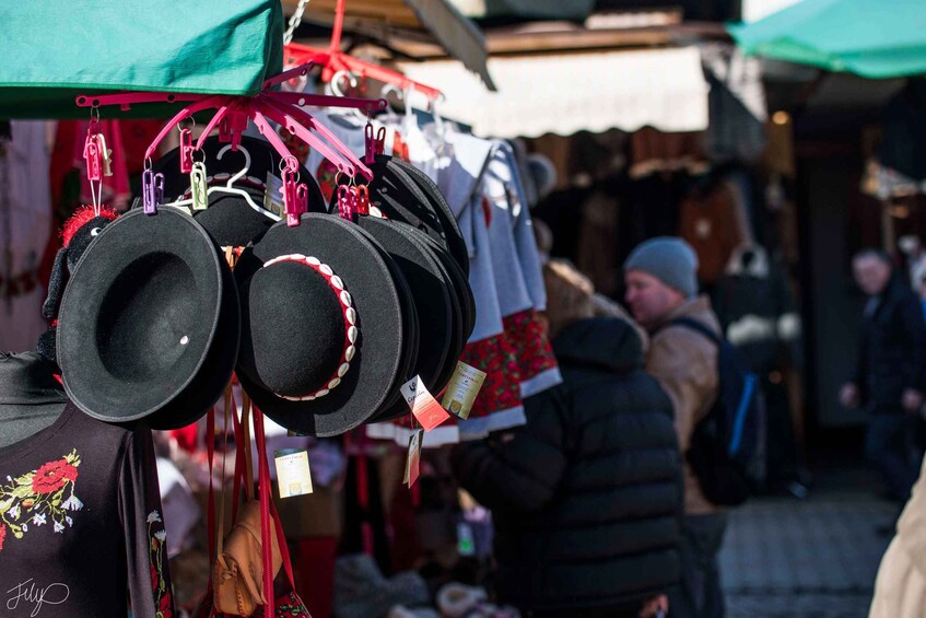 Des chapeaux sont suspendus à un étal de marché, sous une marquise verte. 4