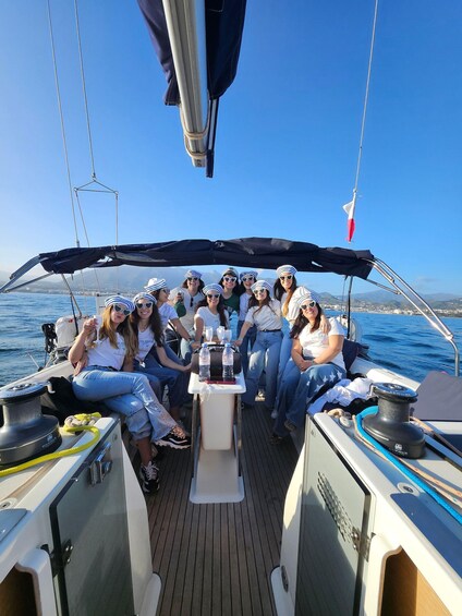 A group of people on a sailboat with a clear blue sky and calm sea. 3