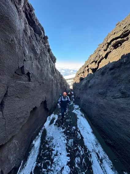 A person walking through a narrow canyon with snow on the ground. 2