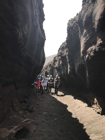 A group of people hiking through a narrow canyon with steep rock walls. 3
