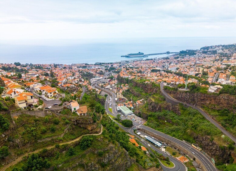A coastal cityscape with winding roads, residential buildings, and a large body of water. 3