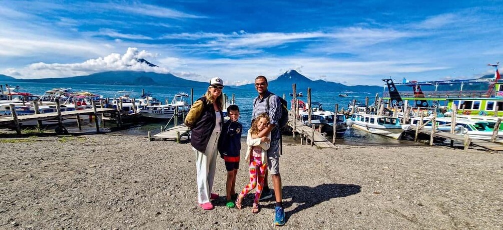 A family on a beach with boats and a mountain in the background. 5