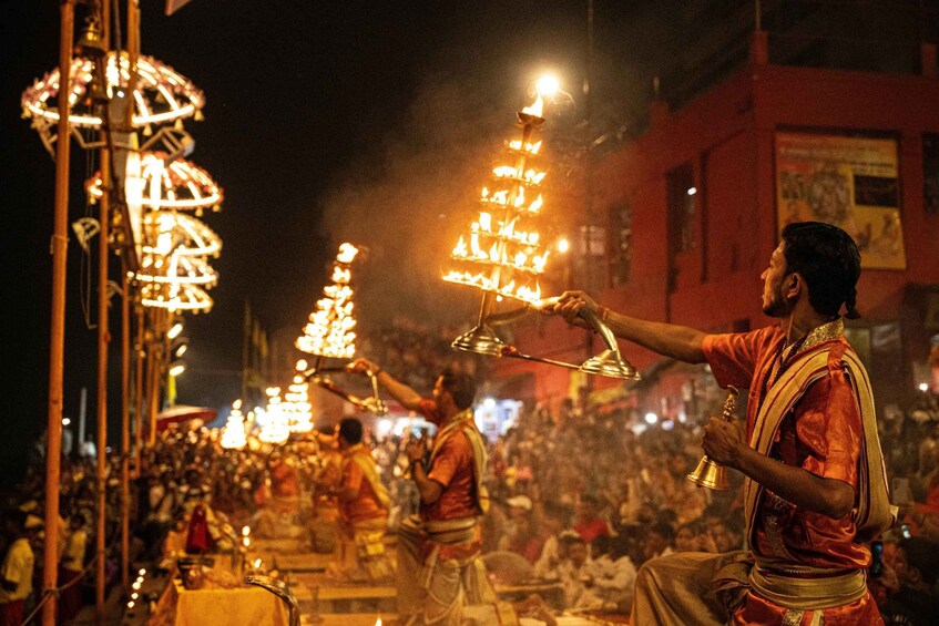 A nighttime street scene with people holding lit lamps and a crowd gathered around. 5