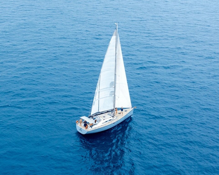 A sailboat with a crew on a calm blue sea. 5