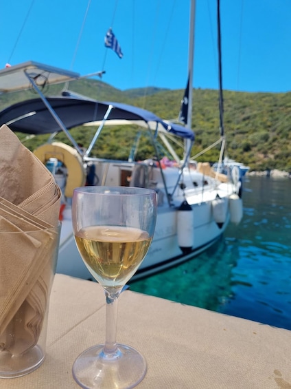 A glass of white wine on a table with a sailboat in the background. 5