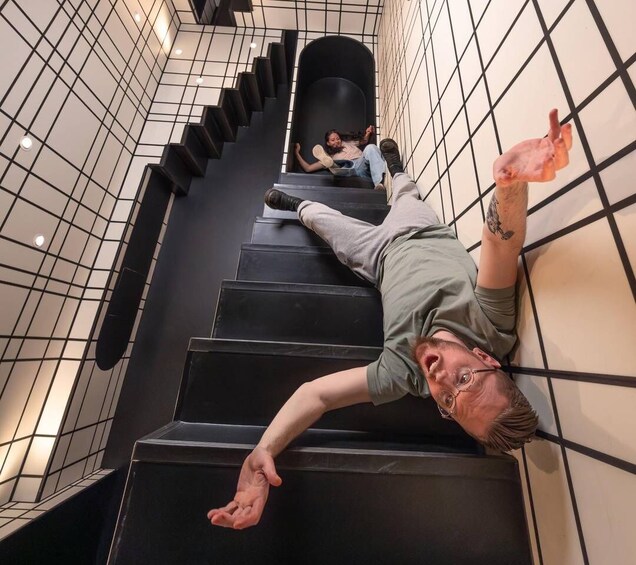 Una persona recostada en una escalera con un fondo de pared de azulejos. 2