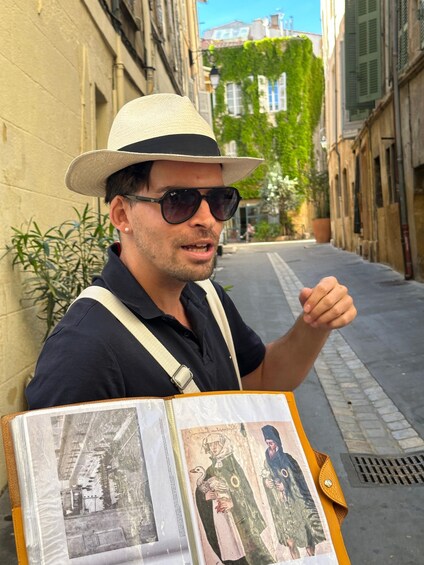 A person with a hat and sunglasses holding a book with pictures. 1