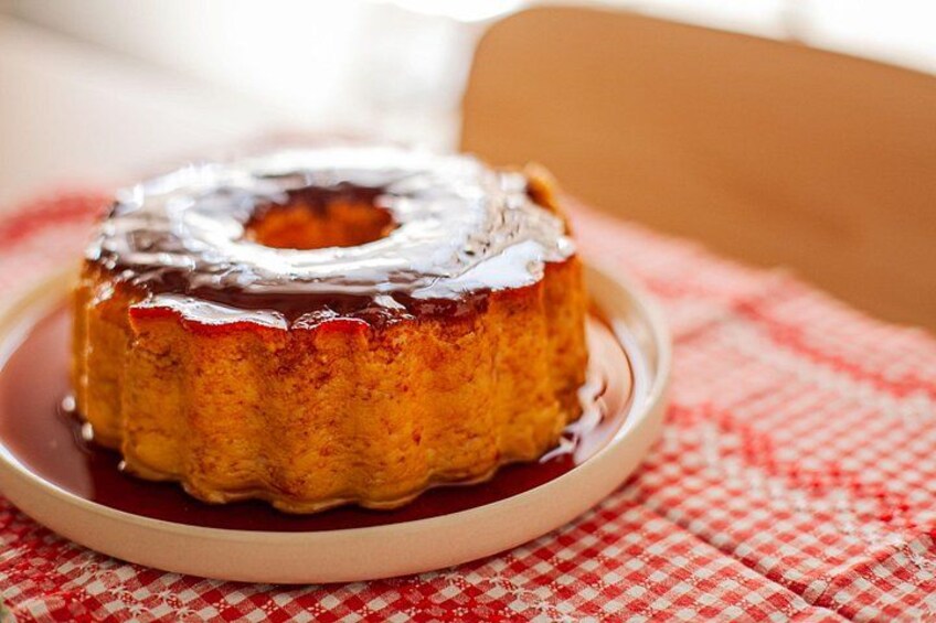 Un flan de caramelo sobre un plato con salsa roja, sobre un mantel a cuadros. 4