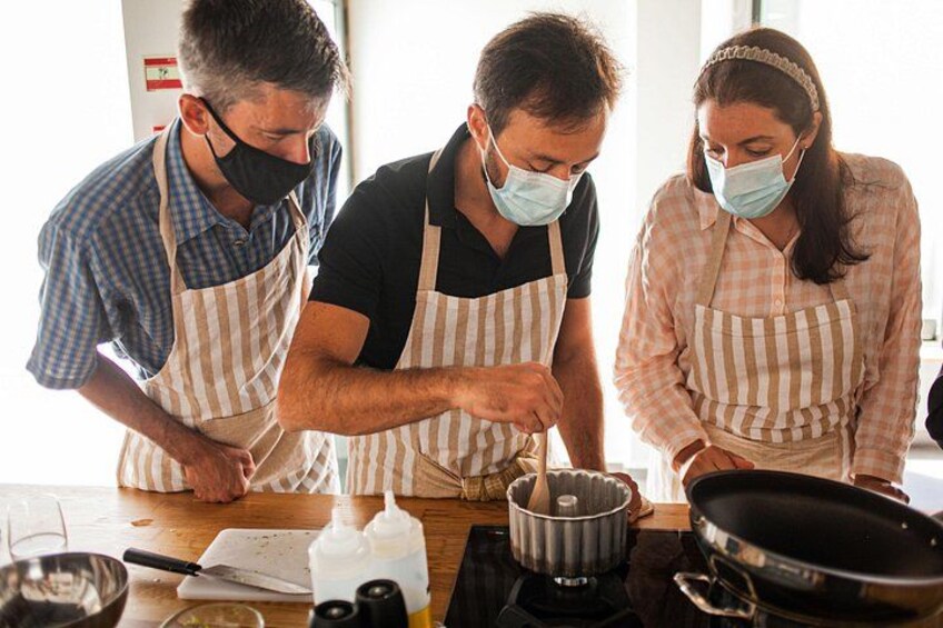 Tres personas con delantales cocinando en una estufa. 2