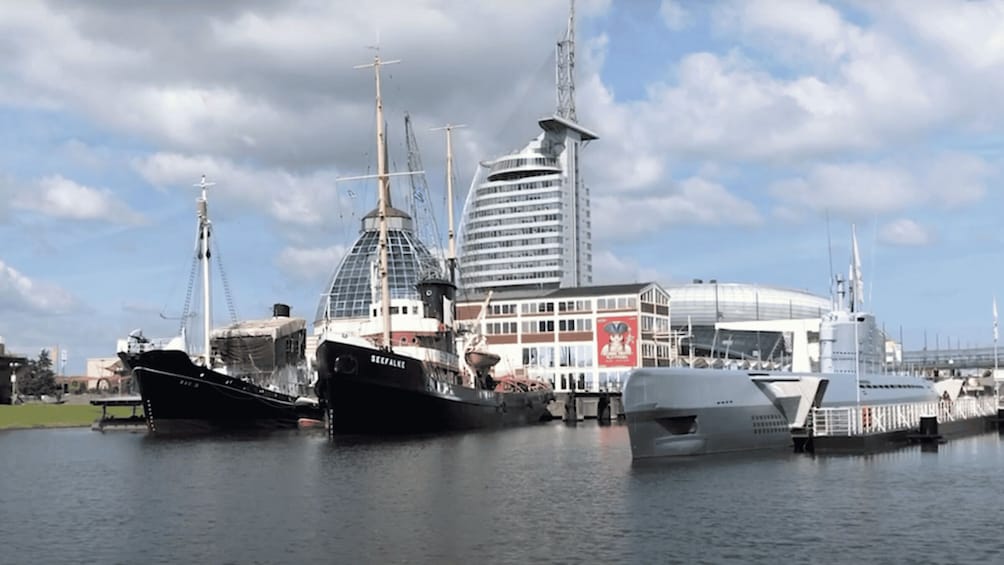 A marina with several boats docked, a modern building with a dome, and a cloudy sky. 1