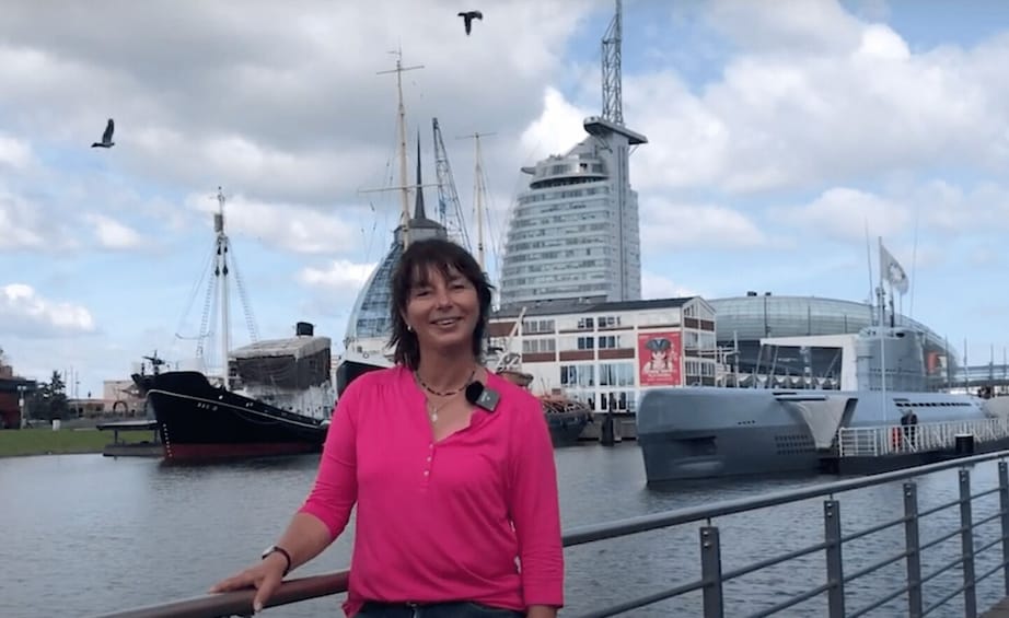 A person standing by a waterfront with a cruise ship and tall buildings in the background. 5