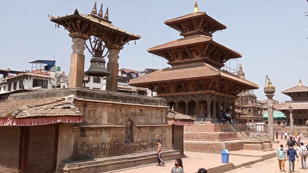 A traditional multi-tiered pagoda with intricate carvings, a bell tower, and a temple with a statue. 5