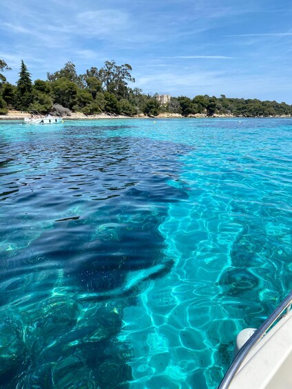 Clear turquoise water, a boat, and a coastal landscape with trees and buildings. 1