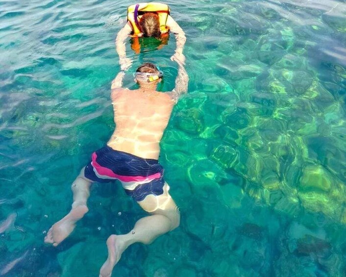 A person swimming in clear blue water with a snorkel and mask. 1