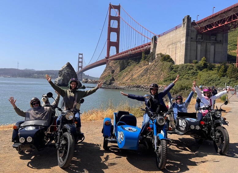 A group of motorcyclists with raised arms, a blue motorcycle, and the Golden Gate Bridge in the background. 5